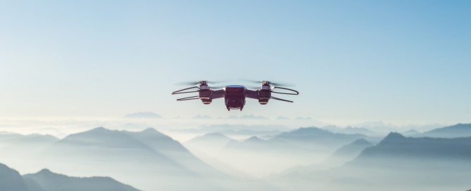 Drohne am strahlend blauen Himmel, im Hintergrund Berge