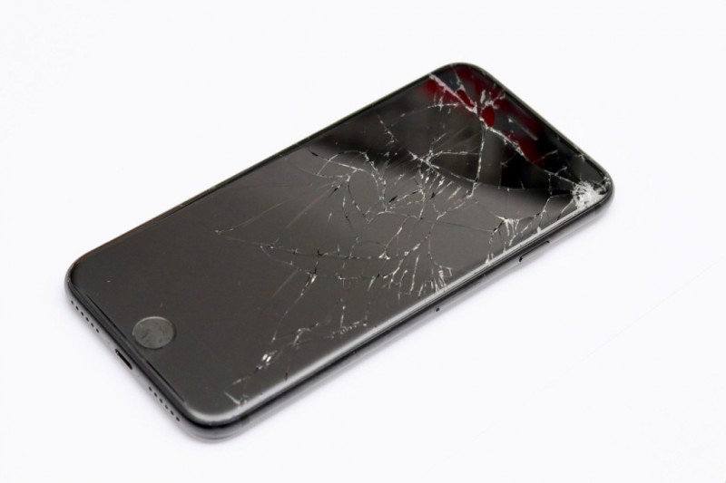Displayreparatur: iPhone mit zersplittertem Display auf weißem Hintergrund